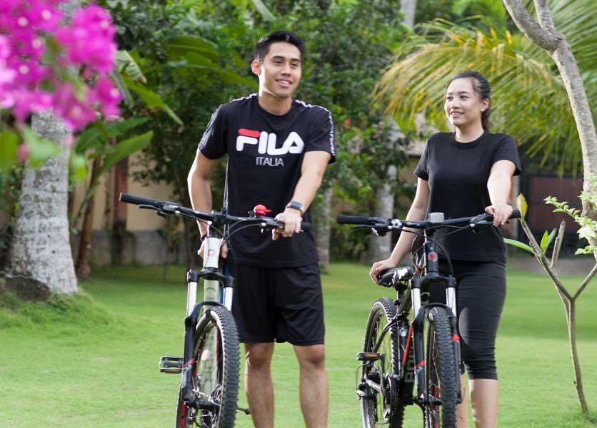 A couple with bicycles at Puri Bagus Candidasa garden